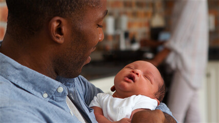 Close Up Of Loving Father Cuddling Sleeping Baby Son In Nursery