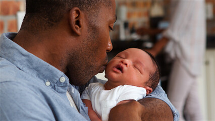 Close Up Of Loving Father Kissing Sleeping Baby Son In Nursery