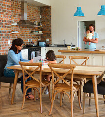 Fototapeta premium Mother At Home Working On Laptop With Daughter Drawing Whilst Father Cuddles Baby Son