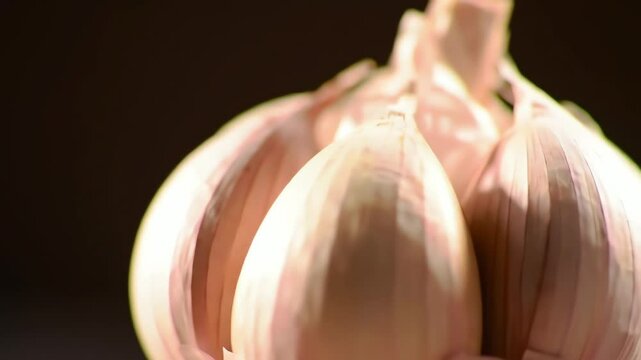 Close-up of a fresh garlic bulb with subtle purple hues and distinct cloves on a dark background