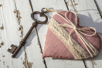 Rustic pink heart with antique key on weathered wood