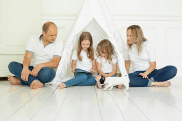 Fototapeta premium Happy family mother father and children using tablet gadget sitting on floor at home