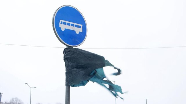 Torn plastic wrap flutters at bus stop in a snowstorm