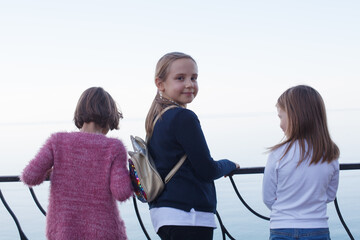 Pretty little children looking at sea. Happy young girl friends back