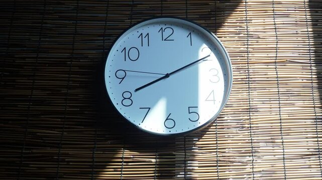 Clock light timelapse revealing changing shadow patterns on woven bamboo blind during afternoon sun