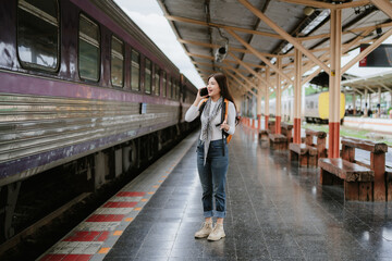 A pretty Asian female tourist using a phone at a train station.