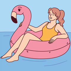 Young woman in swimsuit relaxes on inflatable pink flamingo in pool enjoying summer vacation and sunny weather