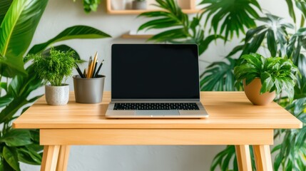 Fototapeta premium Laptop and Plants on Desk: A modern laptop with a blank screen sits on a light wood desk surrounded by lush greenery, creating a serene and productive workspace.