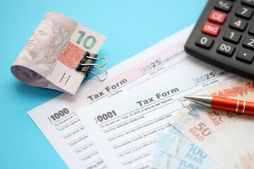 Brazilian reais banknotes with calculator and tax form. The current Brazil real money bills and tax...