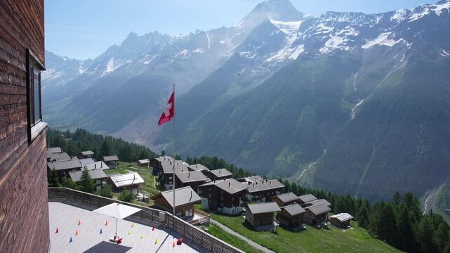 Scenic view of rockfall with gravel and dust at L&ouml;tschental Valley in the Swiss Alps with flying Swiss flag seen from viewpoint at Lauchernalp. Movie shot June 19th, 2025, Wiler, Switzerland.