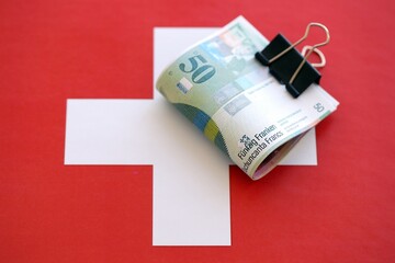 Swiss franc banknotes and flag. The current francs money bills lies on flag in big amount. The...