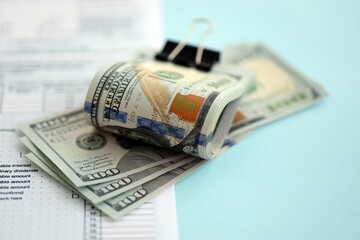 Big amount of United States USD dollar bills on table with 1040 individual income tax return form. Concept of taxation and accounting in United States