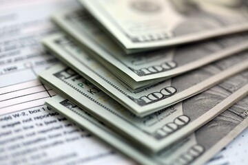 Big amount of United States USD dollar bills banknotes on table with 1040 individual income tax...