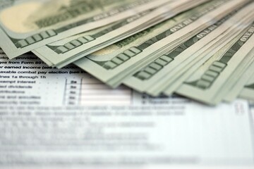 Big amount of United States hundred dollar bills in bunch on table with individual income tax...