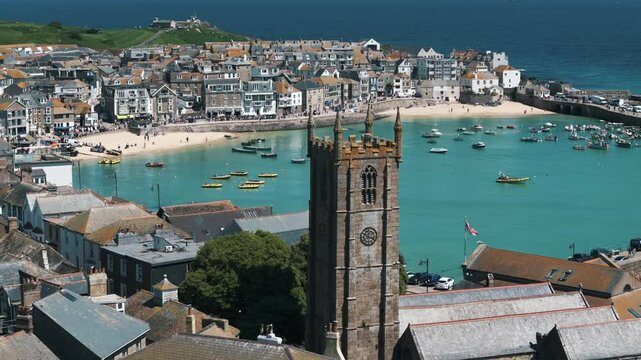 Right establishing aerial orbit around Saint Ives church revealing coastal town and blue sea