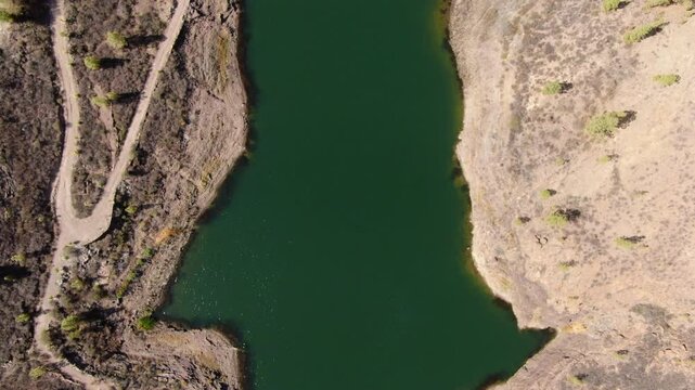 Aerial perspective of El Mulato dam, showcasing the deep green water against the arid landscape of Gran Canaria