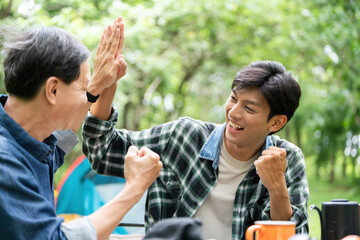 Family engagement. A father and son sharing a high five in a vibrant outdoor environment.