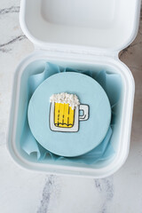Small bento cake with blue cream cheese frosting decorated with a glass of foaming beer drawing in a gift box. Trendy cake as a gift for a beloved man