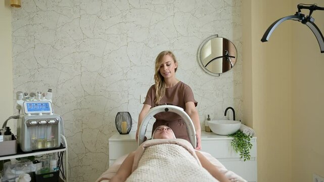Beautician preparing led chromotherapy treatment for client