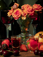 Still life with rose flowers, summer fruits, bottles of wine and a glass of wine. Pomegranate, cherry, sweet cherry, strawberry and watermelon. Alcohol. The still life is stylized as an old painting.