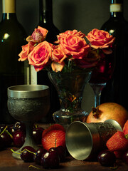 Still life with rose flowers, summer fruits, bottles of wine and a glass of wine. Pomegranate, cherry, sweet cherry, strawberry and watermelon. Alcohol. The still life is stylized as an old painting.
