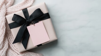 A beautifully wrapped pink gift box with a black ribbon and a blank tag rests on a marble surface, perfect for conveying love and thoughtfulness for any occasion.