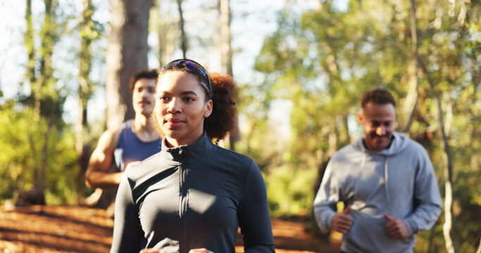 Marathon, woman and smile in forest for fitness, workout and endurance for health or wellness. Cardio club, running group and jog together for competition, practice and team exercise for training