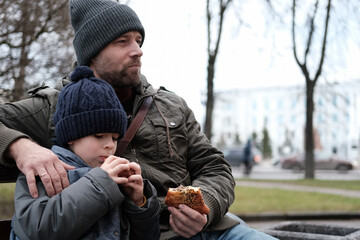 Father and son walking down on sidewalk together. Portrait of a handsome middle-aged man with...