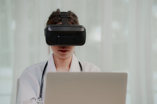 A female medical professional in a lab coat and stethoscope uses a VR headset, interacting with virtual reality in a futuristic healthcare setting.