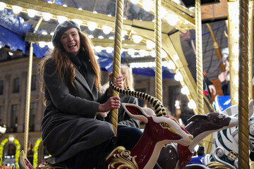 Joyful woman riding Christmas carousel in Paris