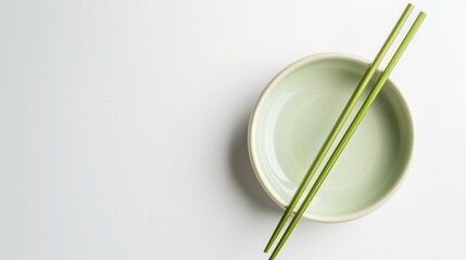 Minimalist food styling showcasing green chopsticks on a ceramic holder against a white background