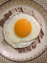 Perfectly cooked sunny-side up fried egg on a decorative plate