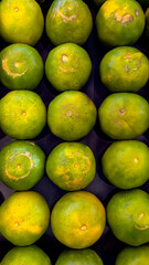 A view of bright green oranges perfect for backgrounds and wallpapers. A view of fresh ripe oranges neatly arranged in the market, Oranges