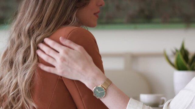 Close up of comforting hand on friends shoulder. Compassion, sympathy and understanding of mental health, women suppoering each other. 