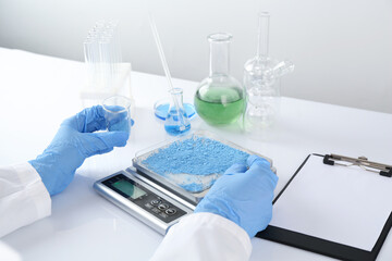 Scientist weighing sample on scales at white mirror table, closeup