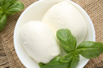 Tasty mozzarella cheese and basil on wooden table, top view