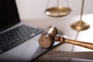 Judge. Laptop, gavel and scales on wooden table in office, closeup