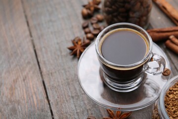 Cup of aromatic coffee, beans, instant powder and spices on wooden table, closeup. Space for text