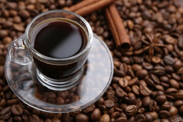 Cup with aromatic coffee, star anise and cinnamon on beans, closeup