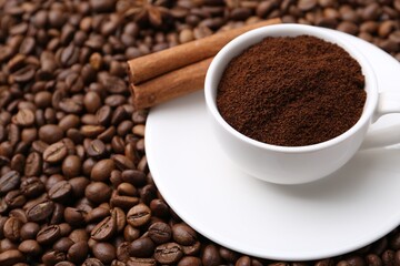 Cup with instant coffee powder and cinnamon on beans, closeup. Space for text