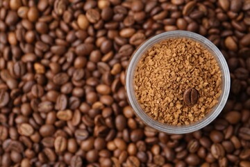 Glass jar with granulated instant coffee on beans, top view. Space for text