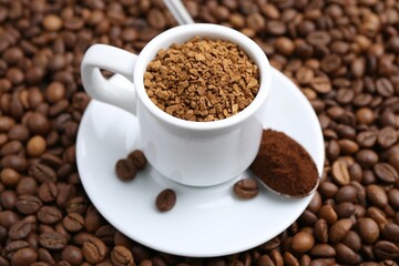 Cup with granulated instant coffee and powder on beans, closeup