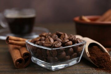 Roasted beans, instant coffee powder and cinnamon sticks on wooden table against brown background, closeup