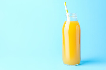 Tasty mango juice in glass bottle on light blue background, space for text
