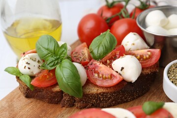 Tasty sandwiches with mozzarella cheese, tomatoes, basil and spices on light table, closeup
