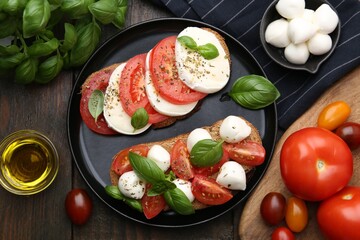 Tasty sandwiches with mozzarella cheese, tomatoes, basil and spices on wooden table, flat lay