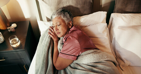 Senior woman, sleeping and above in bed with blanket for warmth or cozy comfort at home. Top view,...
