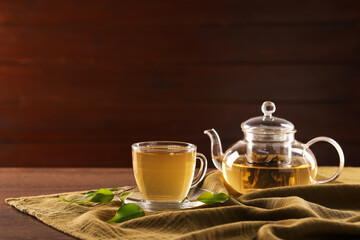 Cup of tasty green tea and teapot on wooden table