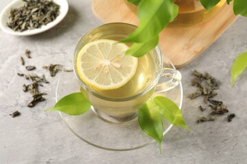 Refreshing green tea with lemon and leaves on light table, closeup