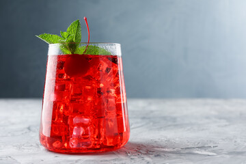 Tasty cherry soda with ice cubes and berry on grey textured table, closeup. Space for text